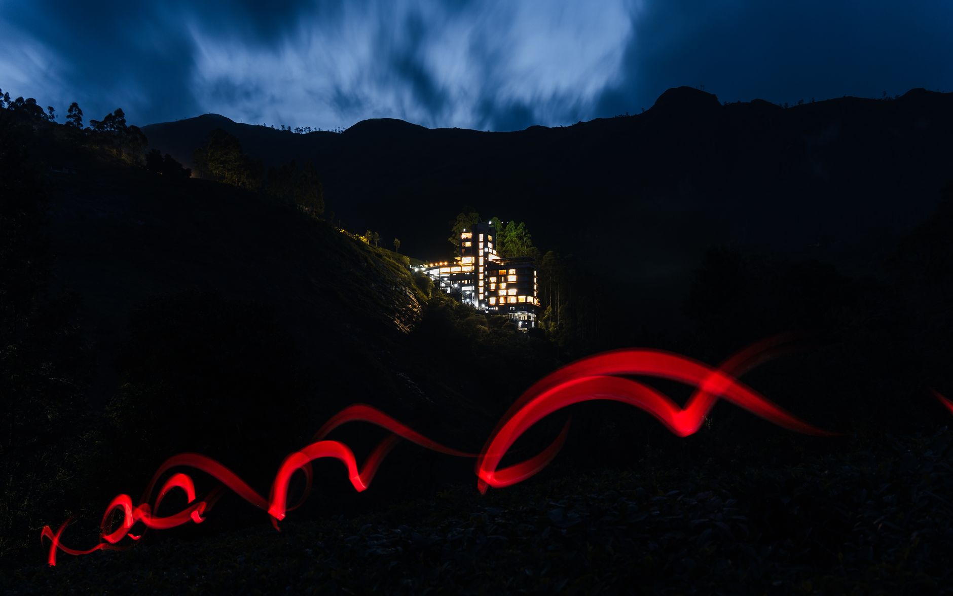 A hotel nestled in Indian mountains at night with a striking red light trail capturing attention. — photograph by Erik Chistov on Pexels